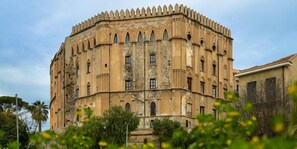 Un bâtiment historique doté d’un coin arrondi, de nombreuses fenêtres en arc de cercle et d’une façade en pierre décorative.