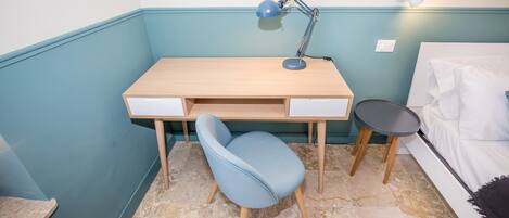 A room with a desk, chair, and bed.