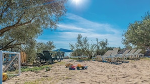 Ein Strand mit Liegestühlen und einem Volleyballnetz.
