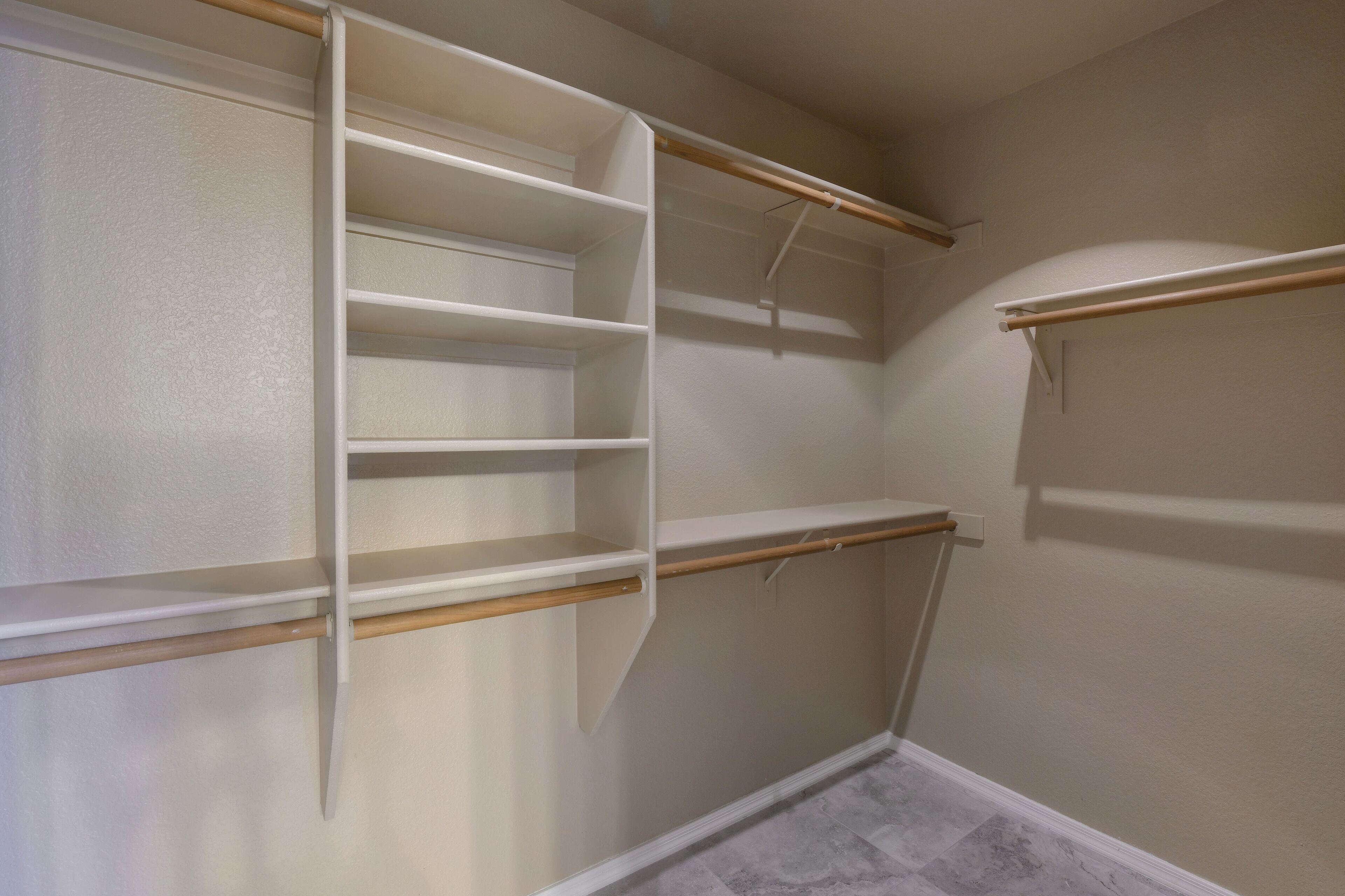 A walk-in closet with open shelves and a wooden rod.