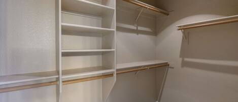 A walk-in closet with open shelves and a wooden rod.