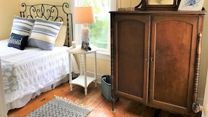 Un dormitorio con cama, mesita de noche, lámpara y un armario de madera.