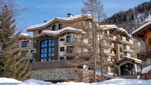 Et hotel med flere etager, en facade af sten, store vinduer og altaner.