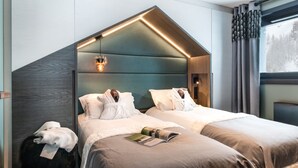 Et moderne soveværelse med to senge, et stort vindue og et unikt loftsdesign.