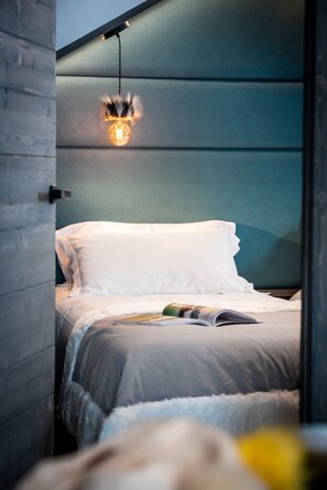 A bedroom with a bed, a hanging light fixture, and a book on the bed. - Chalets Izia (Val-d'Isere)