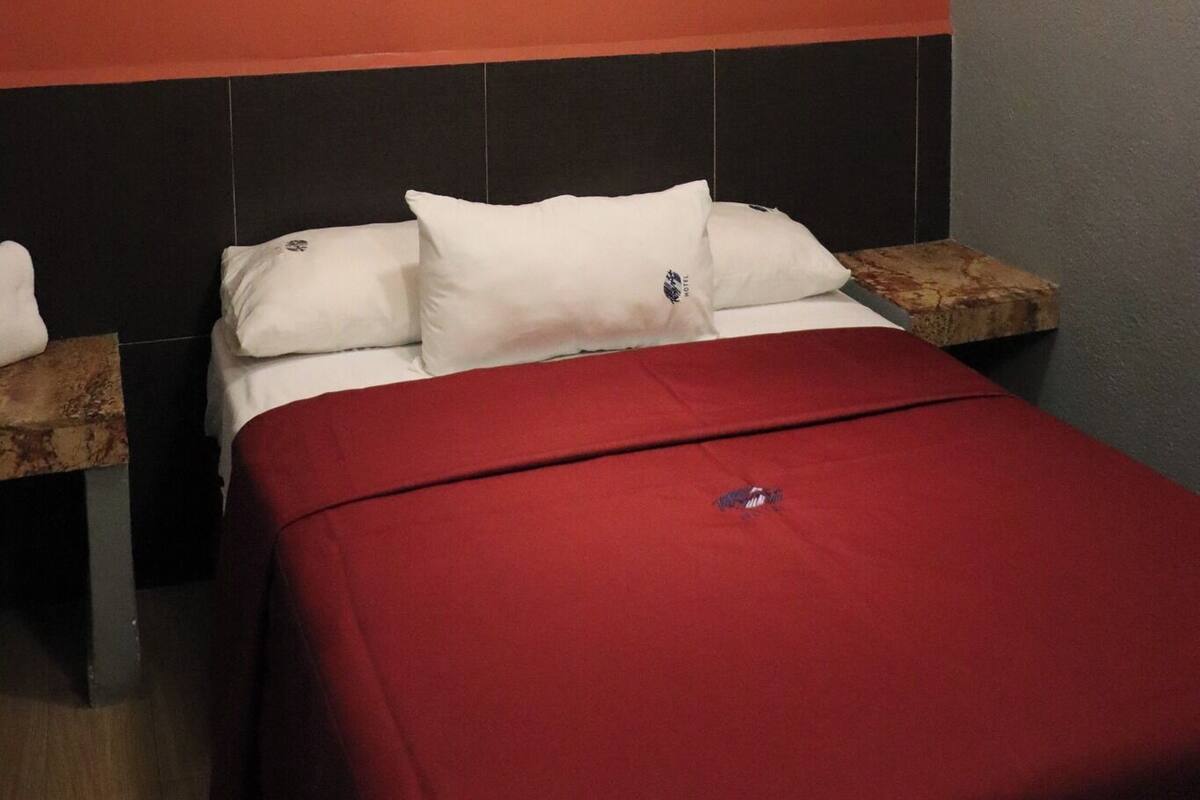 A hotel room with a bed, two nightstands, a framed picture on the wall, and a ceiling light.