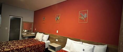 Habitación de hotel con dos camas, una mesita de noche, un espejo y obras de arte en la pared.
