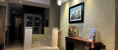 Un vestíbulo de hotel con una escalera, una chimenea y un cuadro enmarcado en la pared.