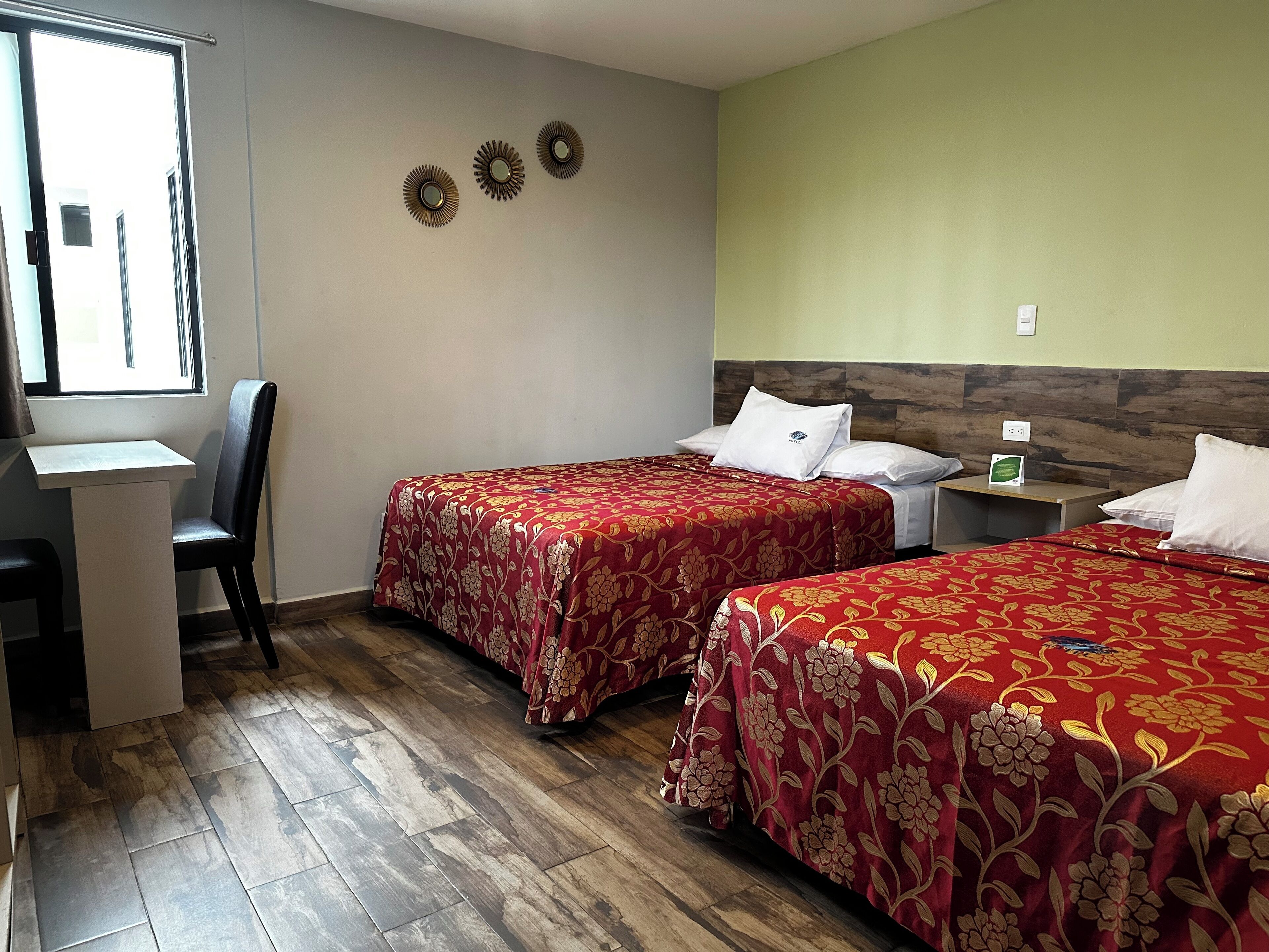 Habitación de hotel con dos camas, un escritorio y una silla.