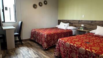 Habitación de hotel con dos camas, un escritorio y una silla.