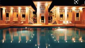 A poolside area with a swimming pool, lounge chairs, and a staircase leading to a covered area. - Happy Hour Cottage Steps Away from Beach (Panama City Beach)