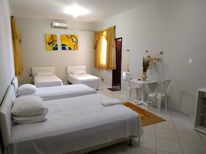 Een hotelkamer met twee eenpersoonsbedden, een tafeltje met stoelen, een vaas met bloemen en een schilderij aan de muur.