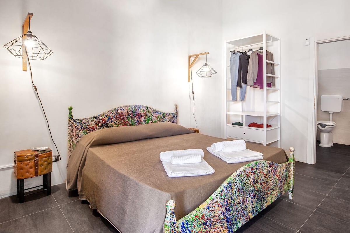 A neatly arranged bedroom with a bed, a wardrobe, and a bedside table.