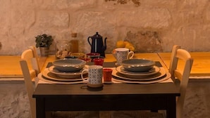 Un comedor con pared de piedra, un cartel con la palabra 'CAFE' enmarcada sobre la mesa, y varios platos y tazas sobre la mesa.