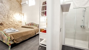 Un dormitorio con cama, armario empotrado y zona de ducha.