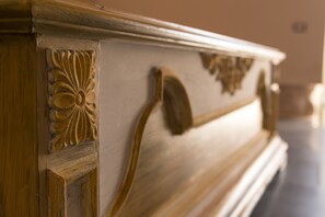 A close-up of a wooden furniture piece with carved floral and leaf patterns. - Giardini Acantus (Rosolini)