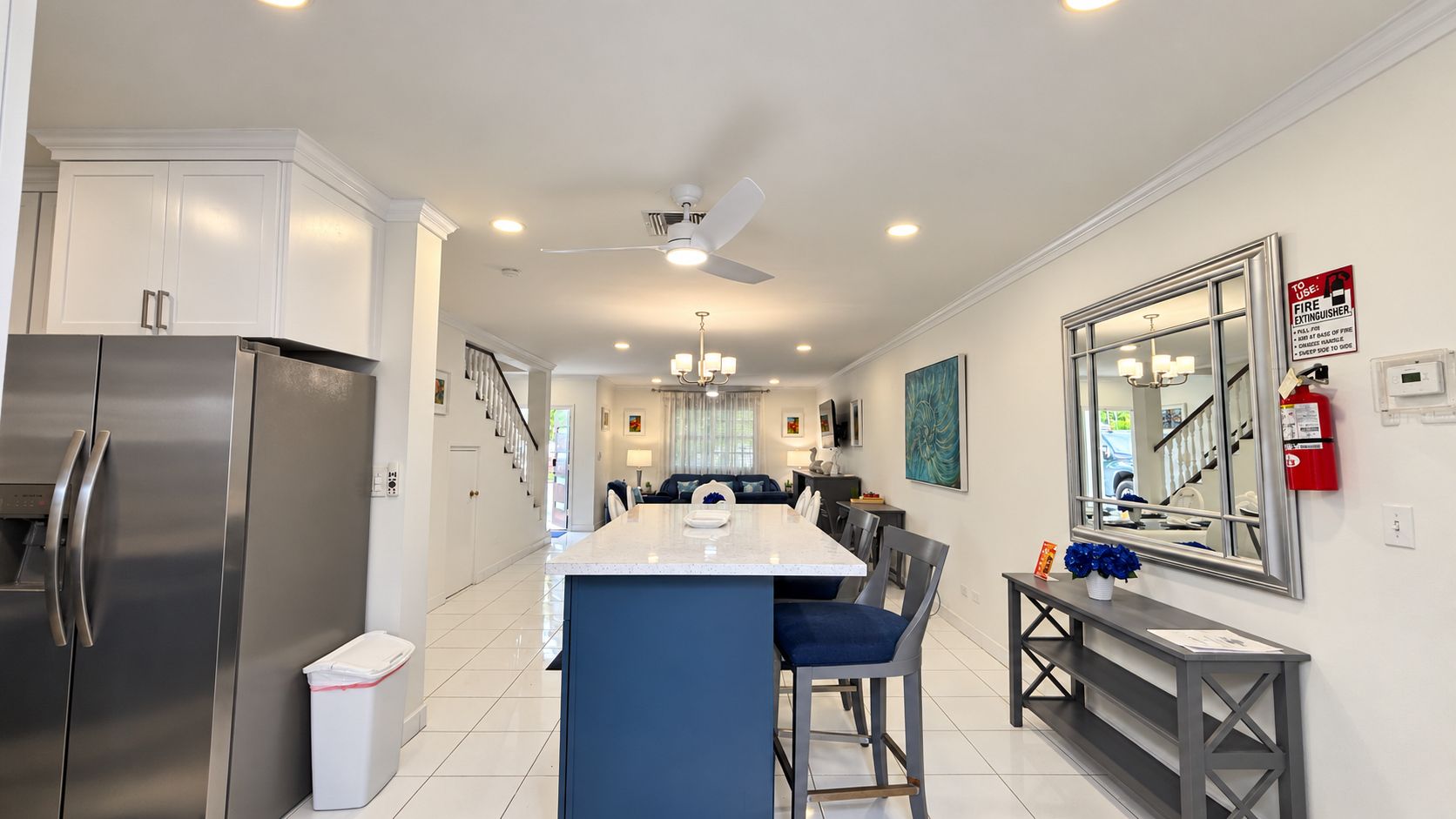 A modern kitchen with a central island, stainless steel appliances, and a dining area with a bench.
