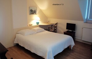 A bedroom with a bed, a desk, a chair, a TV, and a window. - Les Chambres d'hôtes - Les Crépinières (Chartres)
