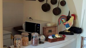 Una cocina con microondas, frascos de comida, una caja de madera y ollas colgantes.