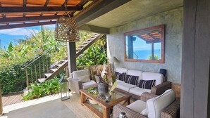 A cozy seating area with wicker furniture, a glass coffee table, and a hanging lantern. - Les Terrasses Suites (Calheta)