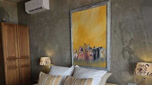 Un dormitorio con una cama, dos mesitas de noche, un armario y un cuadro en la pared.