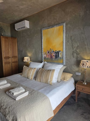 Un dormitorio con una cama, dos mesitas de noche, un armario y un cuadro en la pared.
