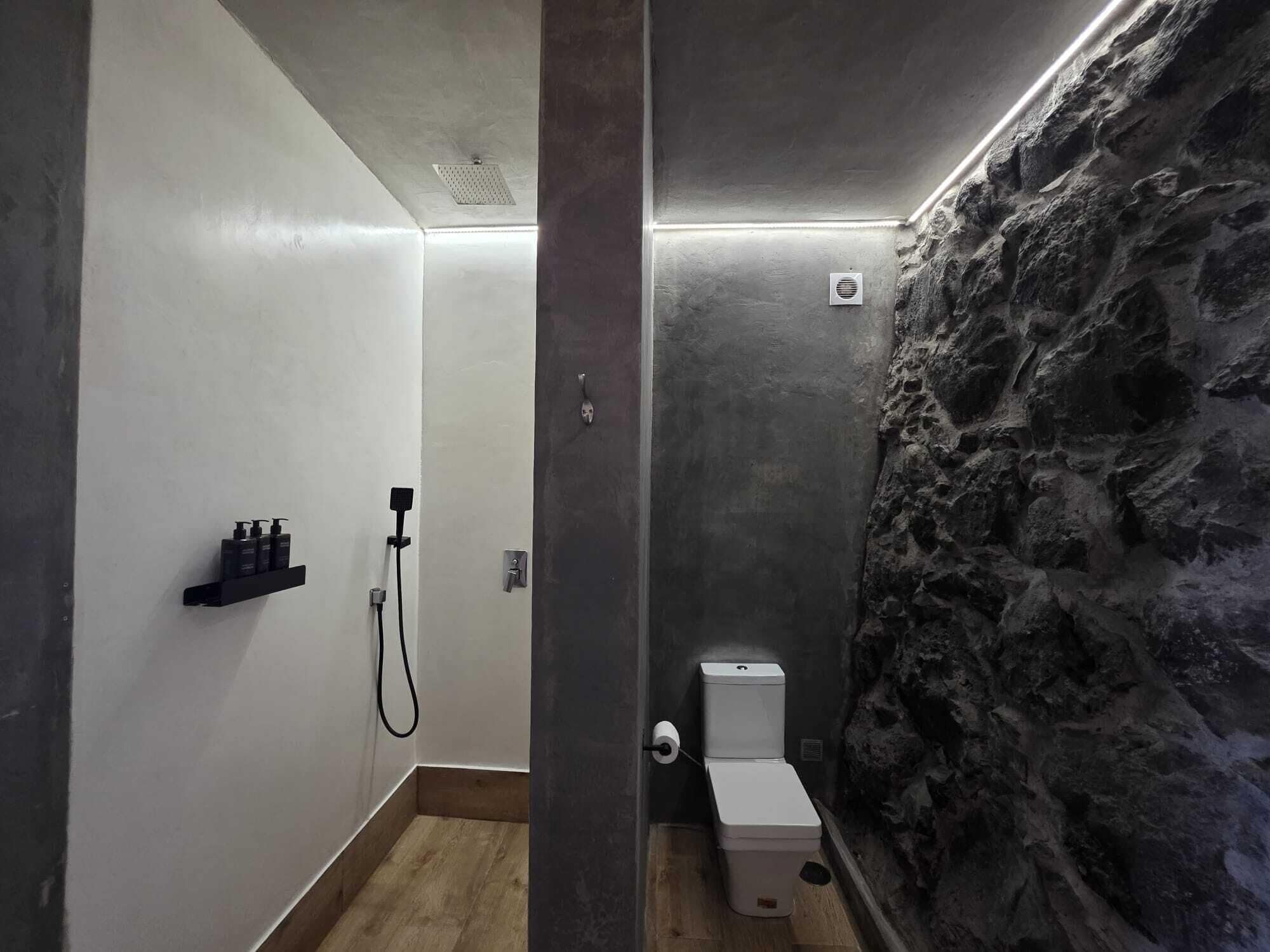 Een badkamer met een douche, toilet en een plank met toiletartikelen.