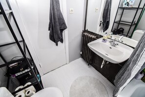 A compact bathroom with a white sink, a mirror, and a radiator. - Apartment V20 (Reykjavik)
