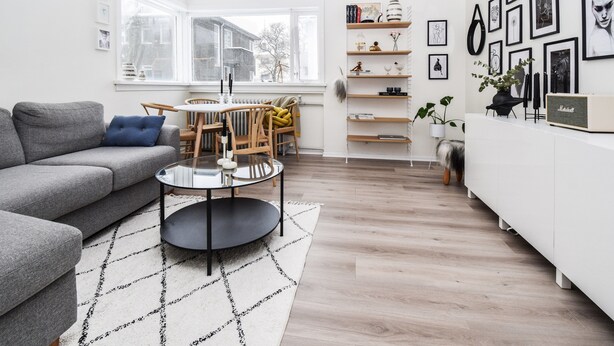 A modern living room with a grey sofa, a round coffee table, and a dining area with a wooden table and chairs. - Apartment V20 (Reykjavik)