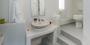A modern bathroom with a white sink, mirror, and toilet. - Villa Mina (Milos)