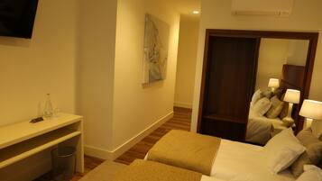 A hotel room with two beds, a desk, a television, a painting, and a mirror.