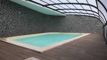 A swimming pool with a tiled wall and a wooden deck.