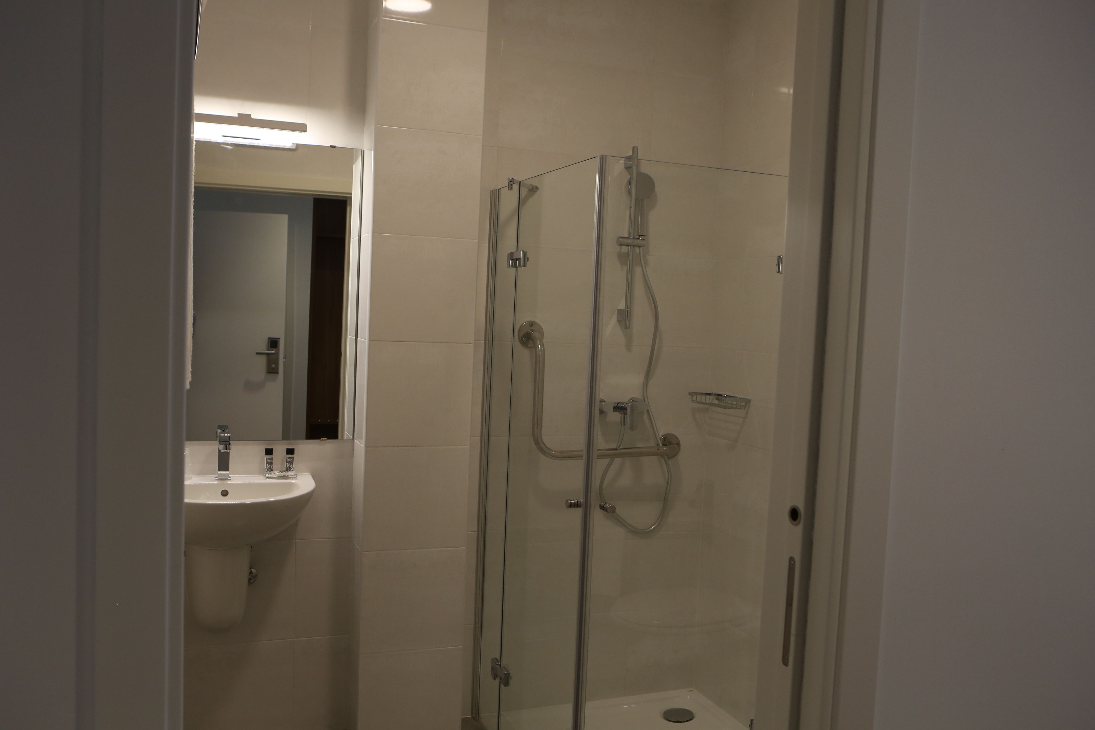 A modern bathroom with a glass-enclosed shower, a sink, and a mirror.