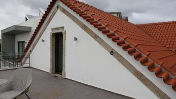 Un edificio con techo de tejas rojas, pared exterior blanca y suelo de baldosas grises.