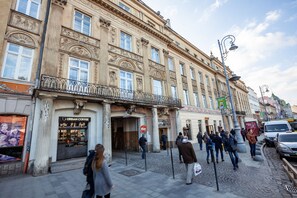 A historic building with ornate architecture, a coffee shop on the ground floor, and a cobblestone street.