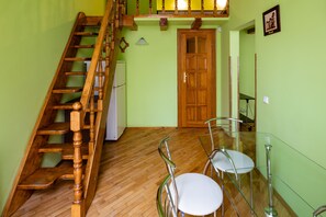 A staircase with wooden steps and a handrail, a wooden door, and a dining area with a glass table and chairs.