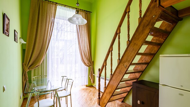 Una habitación con una mesa de comedor, sillas, una escalera y un refrigerador.