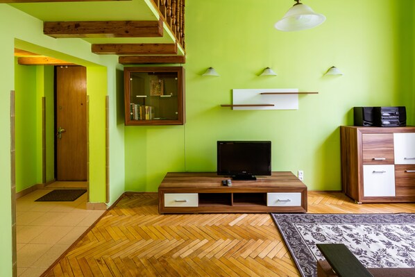A room with a wooden entertainment unit, a television, a white cabinet, and a patterned rug.