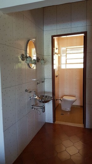 A bathroom with a tiled floor, a sink with a mirror, and a toilet. - Sítio Brasiliano em Mairinque (Mairinque)