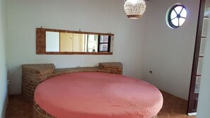 A bedroom with a large bed, a wooden headboard, a mirror, a chandelier, and a window. - Sítio Brasiliano em Mairinque (Mairinque)