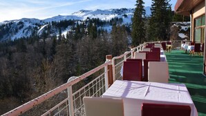 Een restaurant met terras, met uitzicht op een besneeuwd berglandschap.