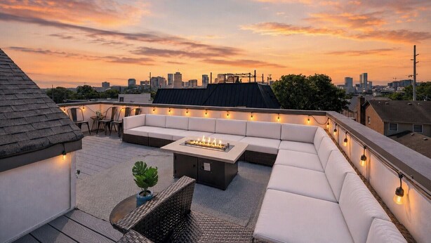 A rooftop terrace with a sofa, a table, and string lights. - Rooftop Terrace · Fire Pit · Wet Bar · City Views (Nashville)