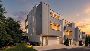 A modern multi-story residential building with a garage, large windows, and a well-maintained lawn. - Rooftop Terrace · Fire Pit · Wet Bar · City Views (Nashville)
