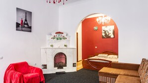 A room with a red sofa, a fireplace, a bed, and a painting of the Eiffel Tower. - Apartments with bedrooms at the center (Lviv)