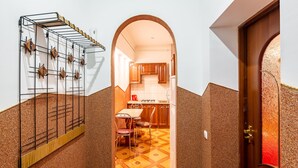 A narrow hallway with a tiled floor, a wooden door, and a kitchen visible through an archway. - Apartments with bedrooms at the center (Lviv)