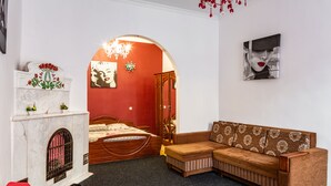 A bedroom with a bed, a sofa, a fireplace, and a mirror. - Apartments with bedrooms at the center (Lviv)