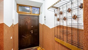 A hallway with a dark wooden door, a patterned rug, and a wall-mounted drying rack. - Apartments with bedrooms at the center (Lviv)