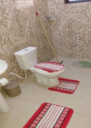 Une salle de bain équipée de toilettes, d’un bidet, d’un lavabo et d’un seau-mop.