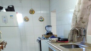 A compact kitchen with white tiles, a sink, a refrigerator, and a microwave. - Casa na praia do Romance Caraguatatuba (Caraguatatuba)