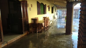 A spacious indoor area with a long table and chairs, wooden doors, and a tiled floor. - Casa na praia do Romance Caraguatatuba (Caraguatatuba)